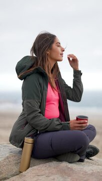 Latin American woman traveler sitting alone in the mountain enjoying coffee and breeze 
