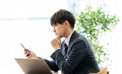 スマホを見て考える男性ビジネスマン
