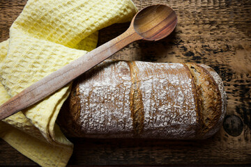 fresh bread with wooden spoon and cloth on wooden background