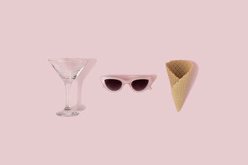 Creative beach accessories glass, sunglass and ice cream cornet on pink background. Vacation and travel concept.
