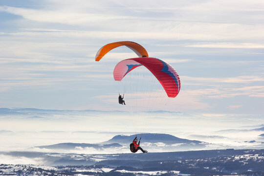 Two paragliders. Paragliding in Auvergne. paragliding flight in the mountains in France. Paragliding over the clouds. Sea of clouds and paraglider. Panorama of the mountains. Puy de D&ocirc;me. Parapentes. 