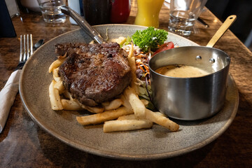 Prime West Coast Rib Eye Steak served with fries, salad and creamy mushroom sauce in a vintage bar and restaurant.