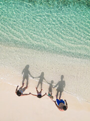 On beach with waves and shadowsA family standing on beach with waves and their shadow