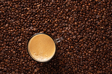 Top view of a lot of roasted coffee beans and a cup of fresh espresso coffee.