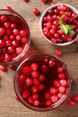 Tasty cranberry juice in glasses and fresh berries on wooden table, flat lay