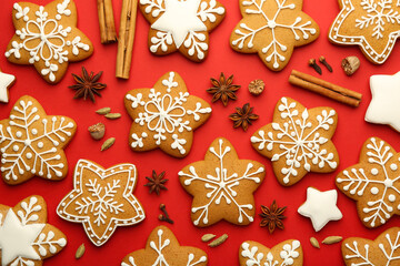 Tasty star shaped Christmas cookies with icing and spices on red background, flat lay