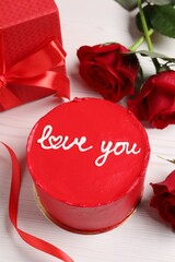 Bento cake with text Love You, gift box and roses on white wooden table. St. Valentine's day surprise