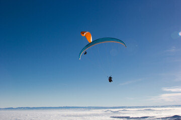 Two paragliders. Paragliding in Auvergne. paragliding flight in the mountains in France. Paragliding over the clouds. Sea of clouds and paraglider. Panorama of the mountains. Puy de Dôme. Parapentes. 
