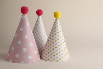 Beautiful party hats with pompoms on beige background. Space for text