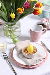 Festive table setting with painted egg in decorative nest. Easter celebration