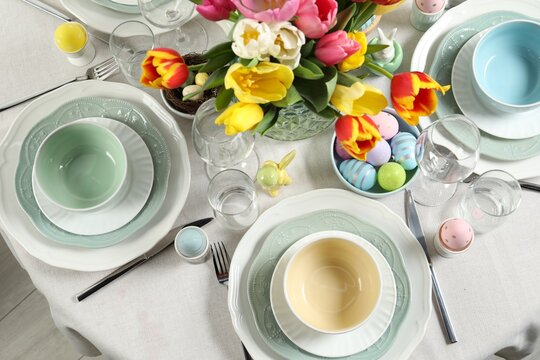 Festive Easter table setting with beautiful flowers and painted eggs, top view