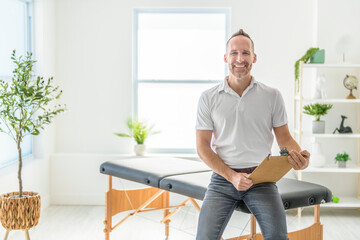 smiling chiropractor holding pad in hospital and looking at camera