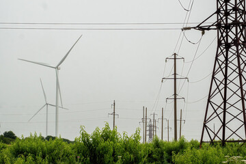 Power lines transmitting produced renewable energy from windmills. Arrays of wind turbines...