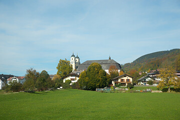 Fototapeta na wymiar historic Basilika St. Michael, tourist resort mondsee, green meadow and blue sky