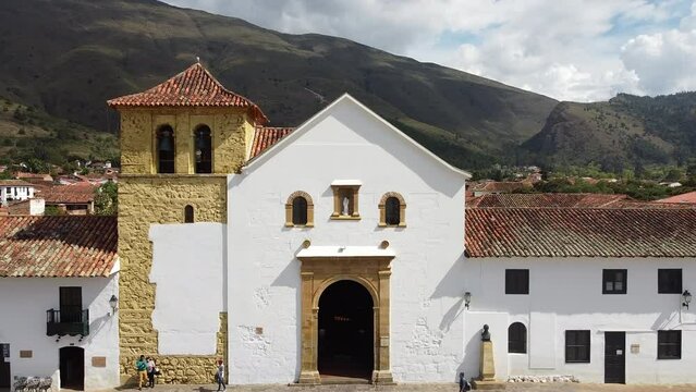 Drone shot of colonial main square in small town of Villa de Leyva, Boyaca, Colombia. Zooming out video shot, showing the church, mountains, trees and greenery.