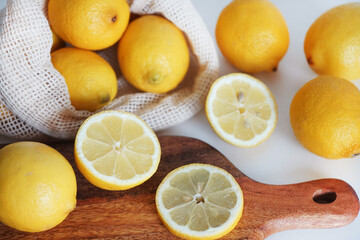 Whole and sliced ​​lemons on a wooden board on a light background