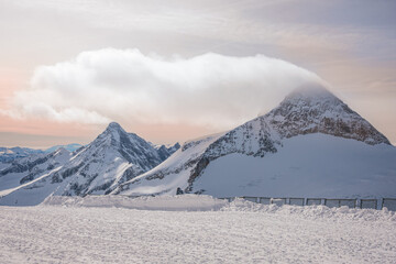 Alpine landscape with peaks covered by snow and clouds, beautiful colors at the top of a glacier.