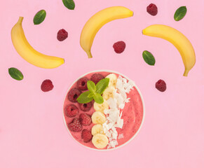 Smoothie bowl with raspberries, banana and coconut chips on the pink background. Top view. Close-up.