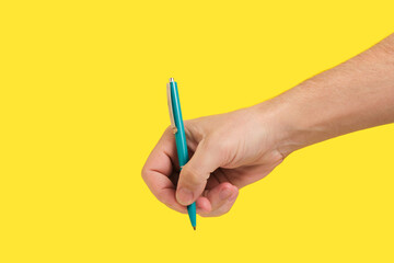 Hand with Green Ballpoint Pen on Yellow. Represents productivity, great for showcasing writing skills office products.