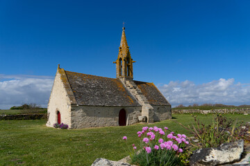 La chapelle Saint-Vio rayonne sous un ciel printanier en Bretagne, son muret orné d'améries...