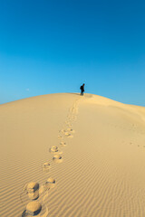 Fototapeta na wymiar A male Photographer step by step walking on Desert Landscape in Abqaiq Dammam Saudi Arabia.