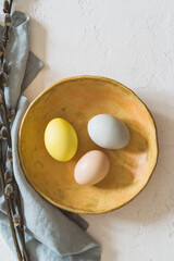 Overhead shot of colourful Easter eggs and twigs on white rustic background - 748940526