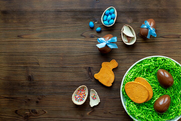 Chocolate Easter eggs in blue ribbon and bunny cookies on wooden background