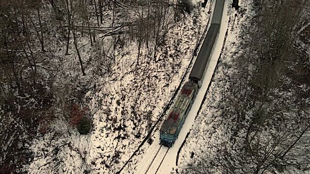 Aerial view of a passenger train running over the Poprad River in the Poprad Landscape Park on a cloudy ,winter day.