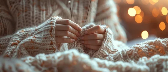 Fotobehang Knitting a cozy sweater, hands and needles at work, soft wool, warm lighting © Fokasu Art