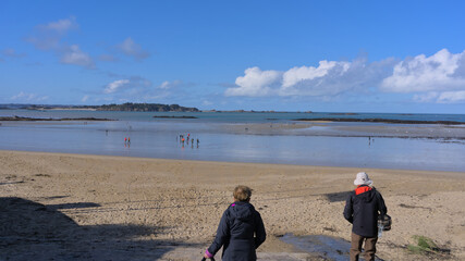 Two elderly people going down the beach of Lancieux, France during low tide
