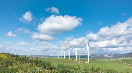Wind turbines in rural landscape with blue sky and clouds, renewable energy concept - 748948546