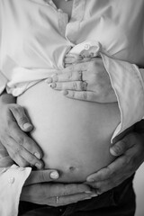 Male hands hugging pregnant belly black and white photography