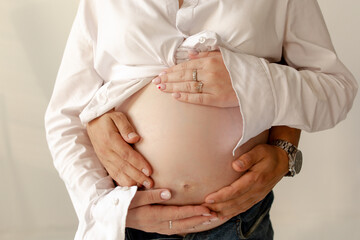 Male hands hugging pregnant belly