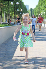 Happy little girl running in city park. Positive childish emotions