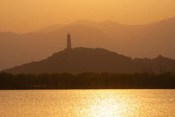 Mountain silhouettes and clouds at sunset behind Kunming Lake, Summer Palace, Beijing, China....