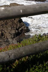 View through wood beams to see rock formation and beach
