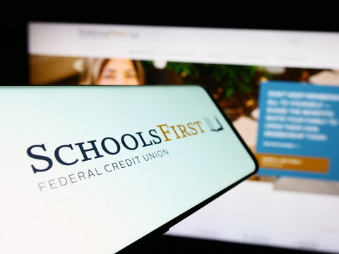 Stuttgart, Germany - 02-23-2024: Mobile phone with logo of American financial company SchoolsFirst Federal Credit Union in front of website. Focus on left of phone display.