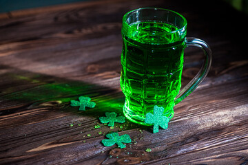 celebrate St. Patrick's Day. Glasses of Green Beer pint on a wooden bar counter, decorated with shamrock leaves. 17 birch. Traditional drink in the light