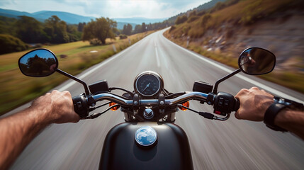 Closeup of two hands on motorcycle handlebars, motorcyclist on paved road.