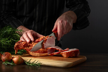 The cook cuts smoked pork on the kitchen table.