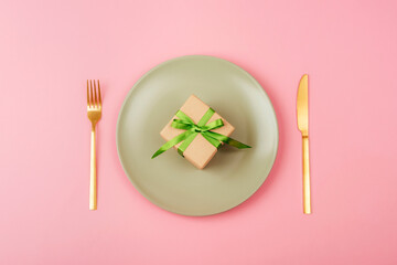 Gift box on light green plate on pink background Mothers day, womens day concept. Top view, flat lay