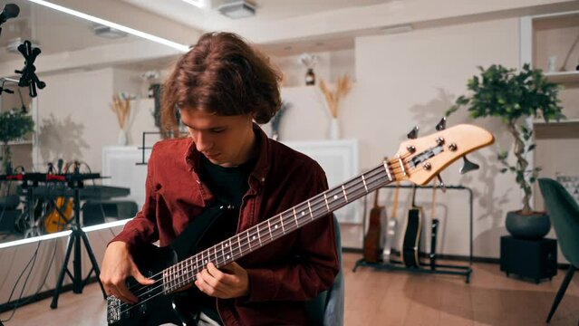 rock artist with long hair with electric guitar during rehearsal playing own track musical instrument string melodies