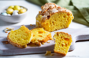 Close-up of a sliced traditional Easter Colomba cake with crunchy almond topping, accompanied by...