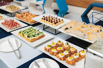 Beautifully decorated banquet catering table, with variety of with different food snacks appetizers on corporate birthday party event or wedding celebration, canape, salad, delicatessen setting