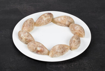 Jellied meat in the shape of a quenelle. On a plate. Dark background. Close up
