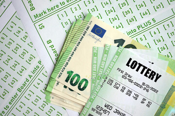 Green lottery tickets and euro money bills on blank with numbers for playing lottery close up