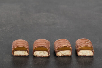 Cookies with caramel in chocolate glaze. In the section. Dark background. Close-up. Copy space
