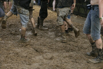 A group of people are walking through a muddy field - 748991570