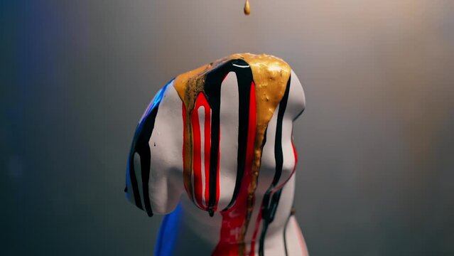 a white sculpture in the shape of a body stands on a barrel, a museum exhibit an artist pours paint on it a performance
