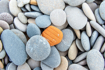 Single Orange Stone Among Smooth Pebble Background